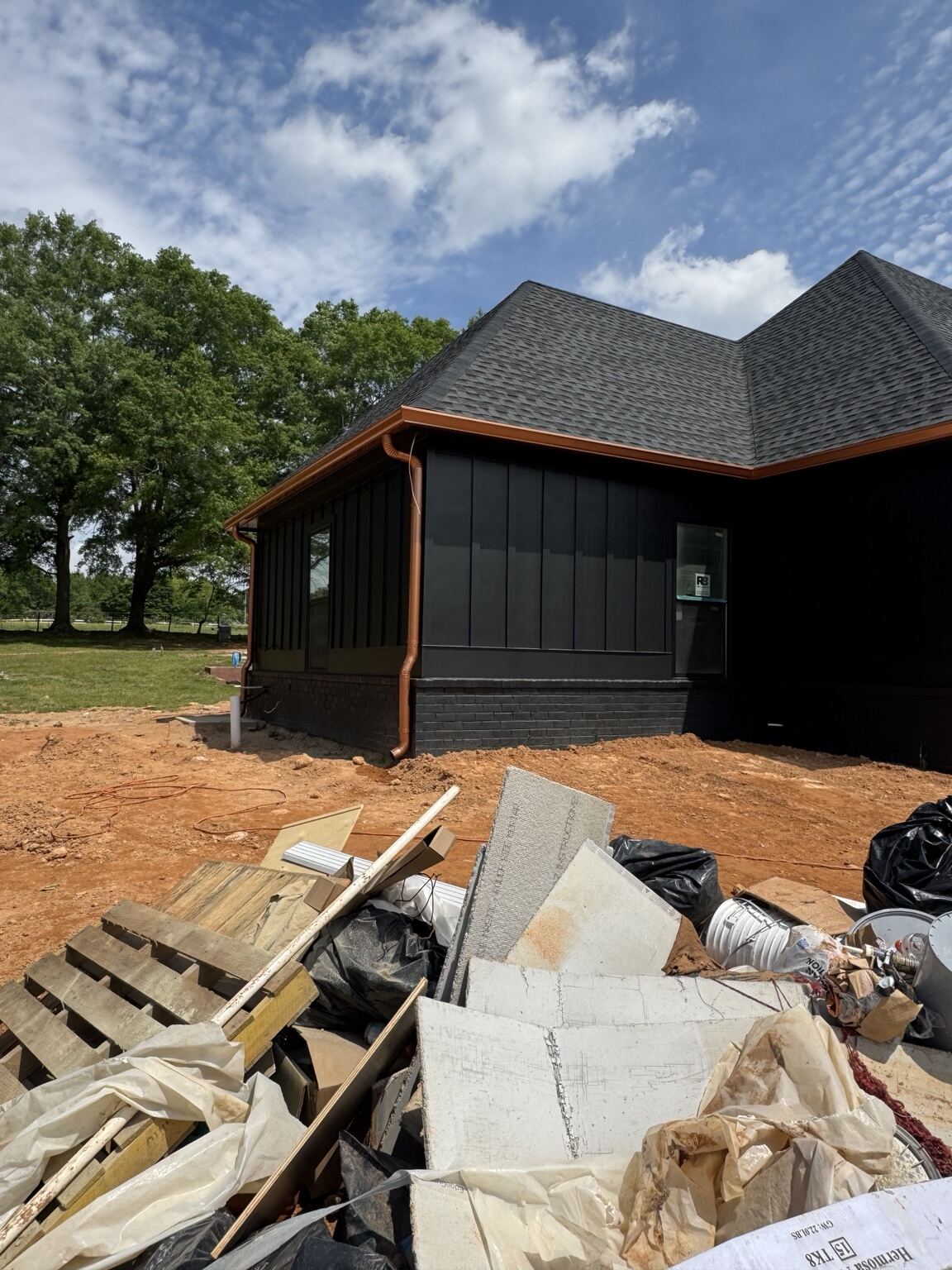 Copper gutters and downspout installed on a black board-and-batten new build