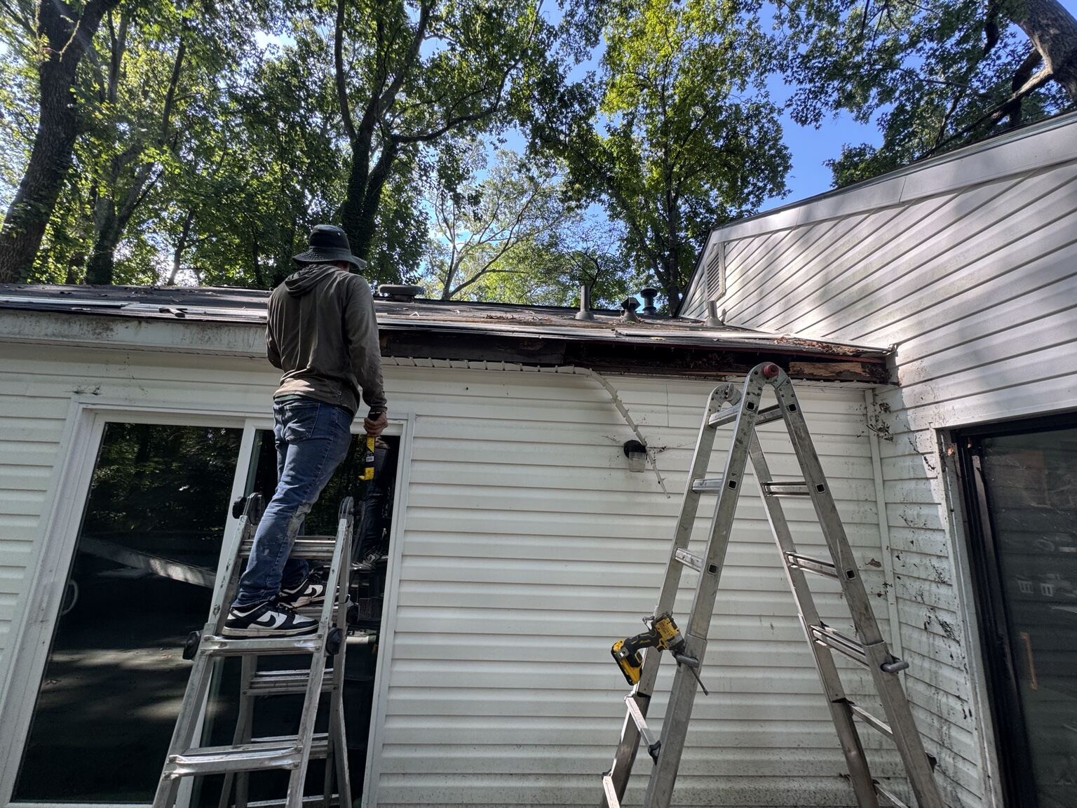 Mr B's Gutters technician on a ladder removing damaged fascia