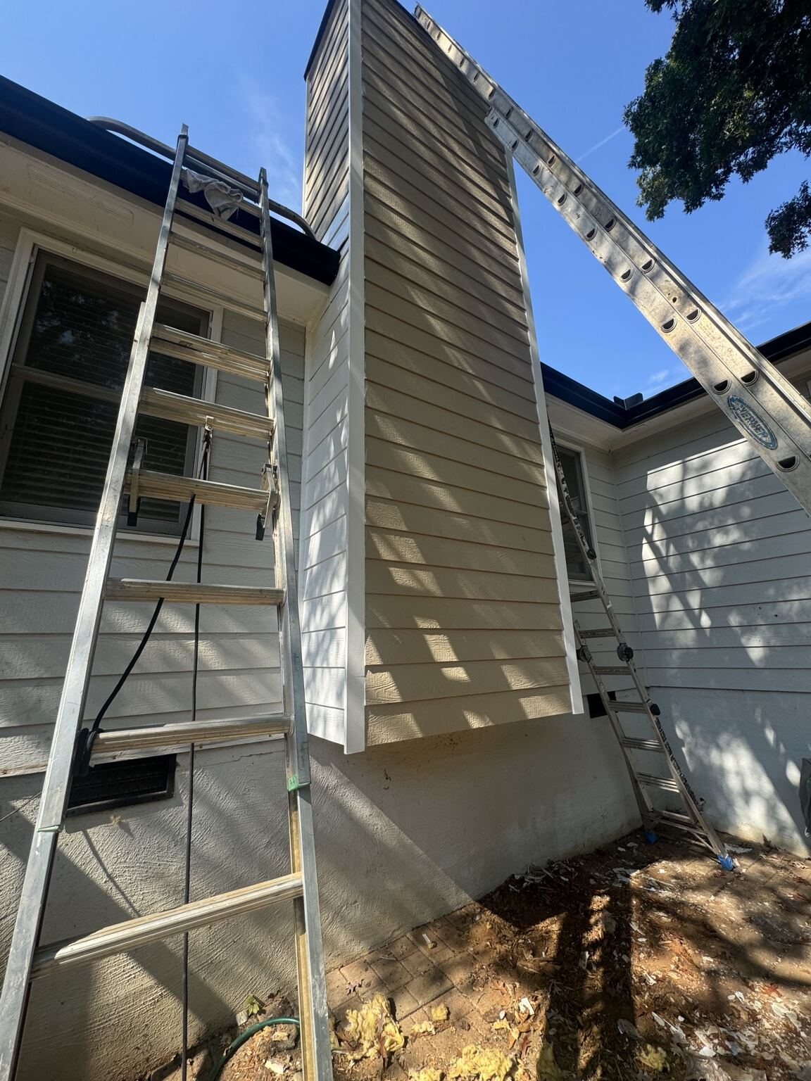 Ladder work along a chimney chase during exterior wood repair
