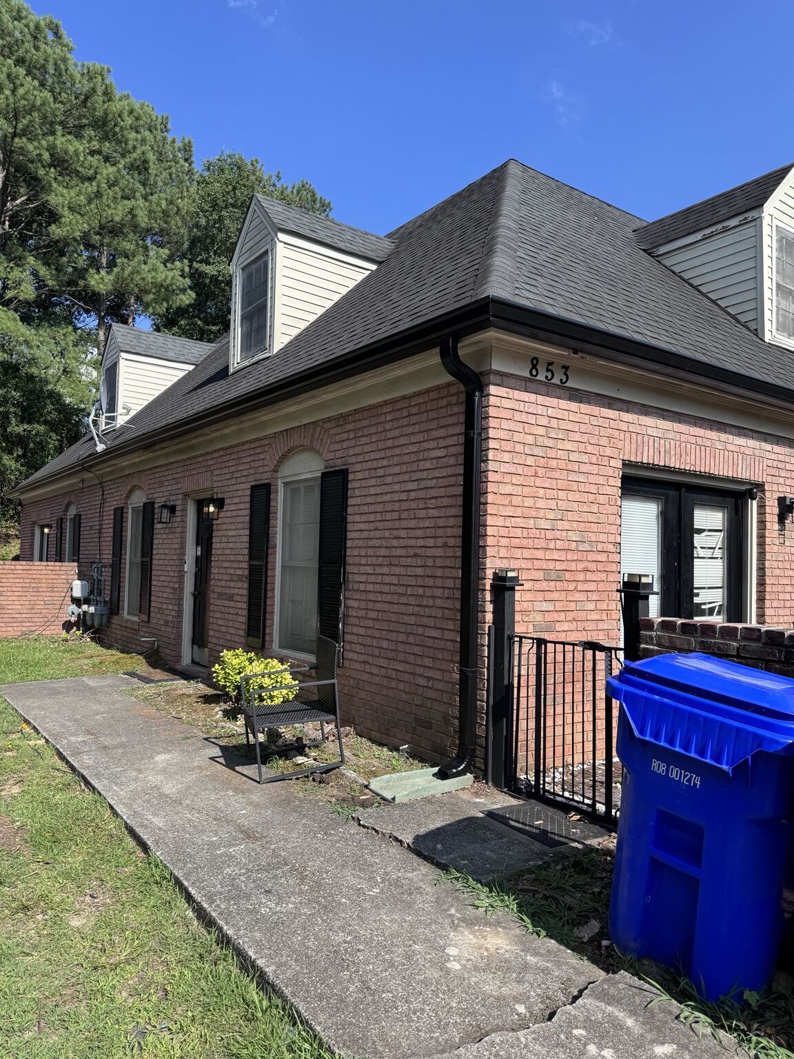 Brick townhome unit with a new black gutter system and downspout